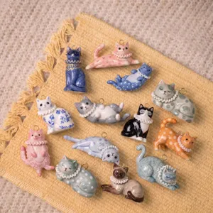 Detailed shot of various cute ceramic cat pendants with metal loops, perfect for DIY jewelry making.