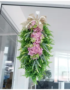 Detailed view of artificial hydrangea teardrop swag with rustic burlap bow for door hanging.