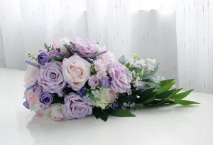 Primo piano dettaglio del bouquet da sposa artificiale a cascata con rose viola e rosa.
