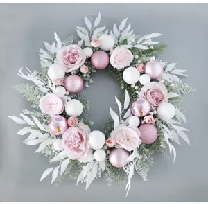 Elegant pink Christmas wreath with roses, white leaves and festive balls for holiday home decor.