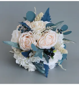Dettaglio bouquet da sposa con rose champagne, foglie blu e bacche per decorazione.