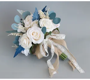 Elegante bouquet da sposa con rose artificiali bianche, foglie blu e bordo in pizzo.
