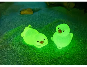 Gros plan détaillé de figurines miniatures lumineuses de petits canards mignons brillant en vert.