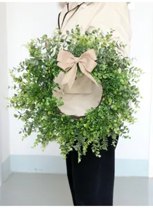 Scatto dettagliato di ghirlanda di bosso verde artificiale con fiocco in iuta da parete.