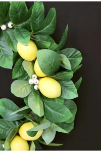 Ghirlanda artificiale di limoni e foglie verdi per decorazione porta e festa murale.
