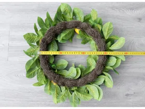 Dettaglio corona di foglie di limone artificiali con fogliame naturale e rattan.