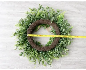 Ghirlanda di bosso verde artificiale per decorazione murale, dettaglio di pianta finta.