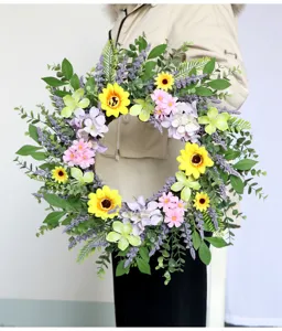 Kunstmatige zonnebloem bloemenkrans detail met groene bladeren en kleurrijke margrieten.