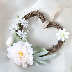 Couronne florale artificielle en forme de cœur avec base en vigne et marguerites blanches.