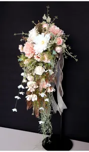 Detalle de ramo de novia en cascada, flores artificiales rosa y blanco, cinta decorativa.
