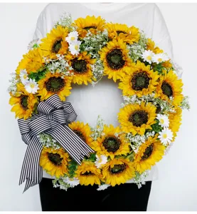 Gedetailleerd overzicht van kunstmatige zonnebloemenkrans met strik voor deurdecoratie.