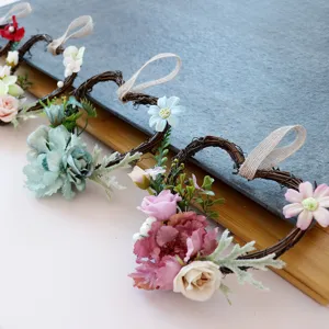 Herzförmiger Rattan Blumenkranz mit Kunstblumen und Juteband für schöne Wanddekoration.
