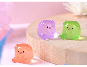 Gros plan de mini figurines de cochon en résine lumineuse, jouet de déco DIY mignon.
