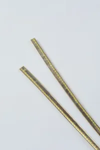Golden metallic finish strap detail with yellow stitching for apparel accessories.