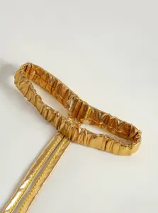Gold metallic elastic strap detail, shiny costume accessory component with fine stitching.