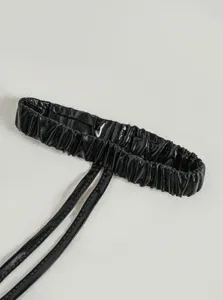 Close-up detail of black glossy patent leather elastic garter strap for sexy lingerie and costumes.