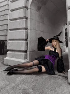 Dark punk witch costume detail shot, gothic black and purple dress with fishnets and hat.