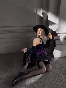 Detail view of the punk gothic witch costume featuring a black dress, purple corset and hat.