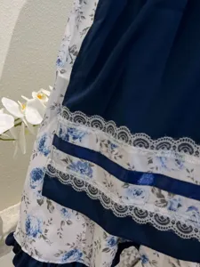 Close-up detail of traditional German Oktoberfest dirndl dress with blue floral print and lace trim.