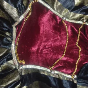 Gothic pirate costume detail view, velvet fabric with delicate chains and charms.