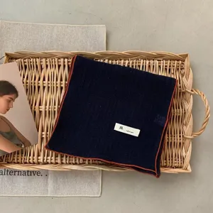 Vue détaillée d'un foulard rétro en coton et lin de couleur unie marine avec bordure marron.