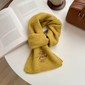Detail view of a cozy yellow knitted scarf featuring chic English embroidery, soft winter texture.