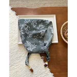 Detailed view of the vintage floral cotton linen triangle scarf with bead-decorated ties.