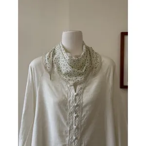 Vintage floral triangular kerchief with delicate lace trim, styled on a classic blouse detail.