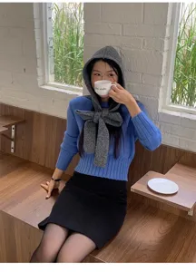 Vista dettagliata della comoda sciarpa con cappuccio in maglia e del maglione blu.