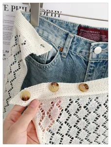 Detailed close-up of stylish denim and white crochet knit layered skirt with buttons.