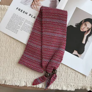 Close-up detail of knit mini scarf with red and blue jacquard pattern and wooden beads.