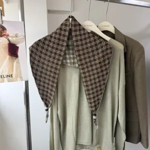 Detailed view of brown plaid triangular scarf hanging on display rack in modern boutique.