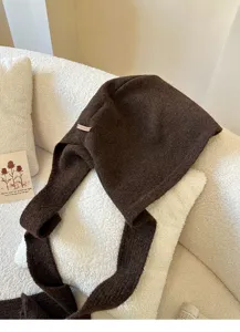 Comodo berretto in maglia marrone con lunghi lacci, dettaglio cappello invernale caldo.