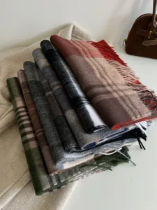 Closeup detail shot of stacked vintage plaid winter scarves with tassels in various colors.