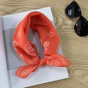 Orange cotton bandana featuring a classic paisley pattern, styled as a chic neck scarf detail.