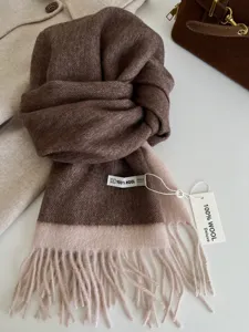 Detailed view of the luxury two-tone 100% wool scarf with fringe hem and product tag.
