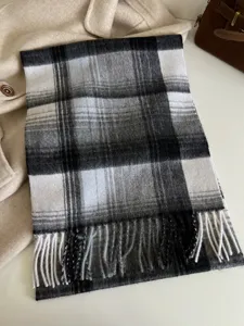 Detail shot of classic black and white plaid wool scarf with fringe, autumn winter warm neck accessory.