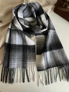 Classic black and white plaid scarf featuring soft fabric and fringe ends. Detail wool shawl.