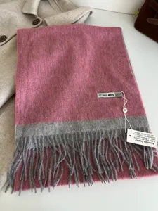Detail view of a luxurious 100% wool colorblock scarf with soft tassels and premium tags.