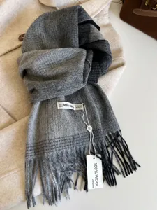 Close-up of grey gradient wool scarf detail, soft texture and delicate fringe trim.