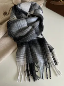 Close-up detail of the classic black and white plaid wool scarf with soft fringe trim.