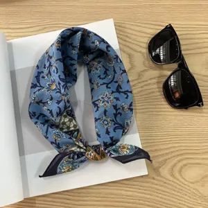 Close up of blue vintage floral paisley small square neck scarf detail on wooden desk.