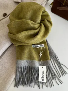 Detail view of the elegant two-tone 100% wool scarf with soft tassels and cozy warmth.