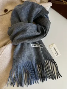 Detailed view of a soft wool tassel scarf in gradient blue grey, cozy winter neck warmer.
