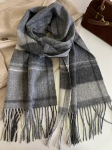 Detail view of grey plaid winter scarf with cozy wool texture and stylish fringe tassels.