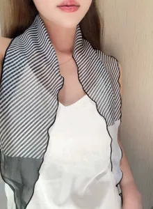 Close-up detail of a chic black and white striped neckerchief with wavy edge design.