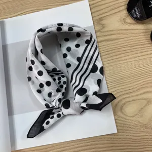 Close-up detail of the black and white polka dot and striped cotton headscarf design.