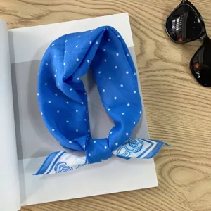Close-up detail of a blue polka dot cotton headscarf tied neatly on a vintage magazine.