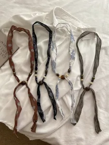 Close-up detail of vintage fabric wooden bead silk scarf necklaces with boho aesthetic style.
