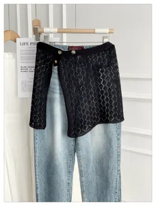 Detail shot of black lace knit wrap skirt layered with blue jeans, stylish street fashion.
